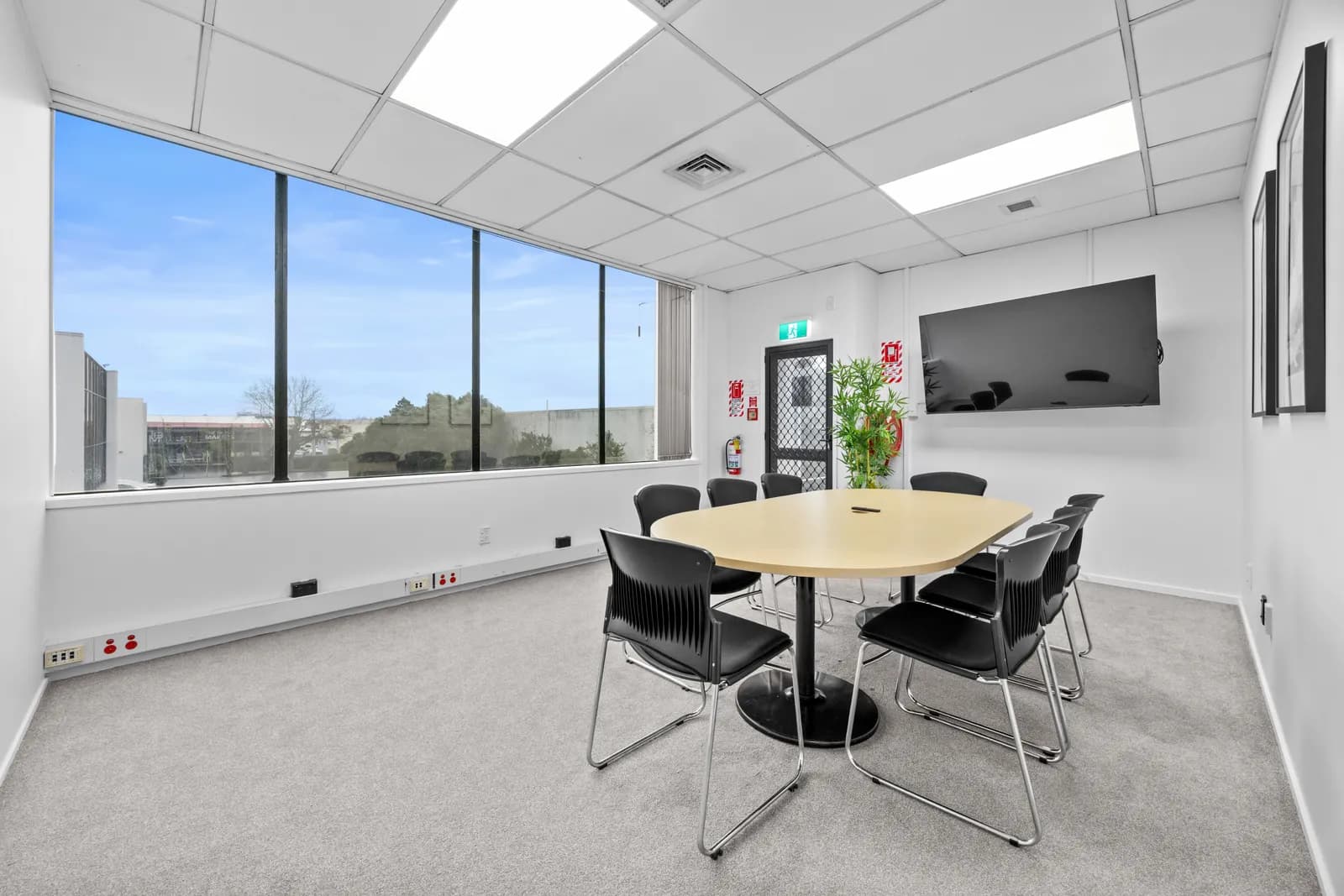 Meeting room with a round table, presentation screen, and city views